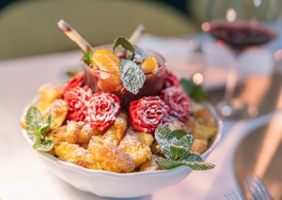 Kaiserschmarrn mit Garnture aus Blumen, Minze und Puderzucker in weisser Schale
