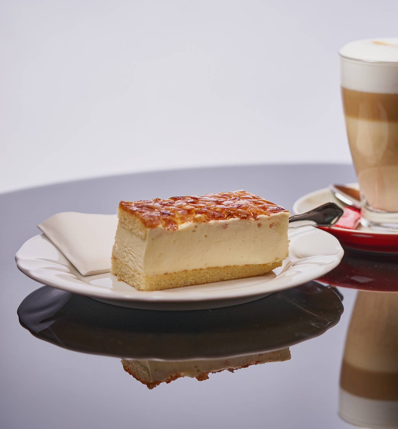 Bienenstich auf weissem Teller mit Latte Macchiato